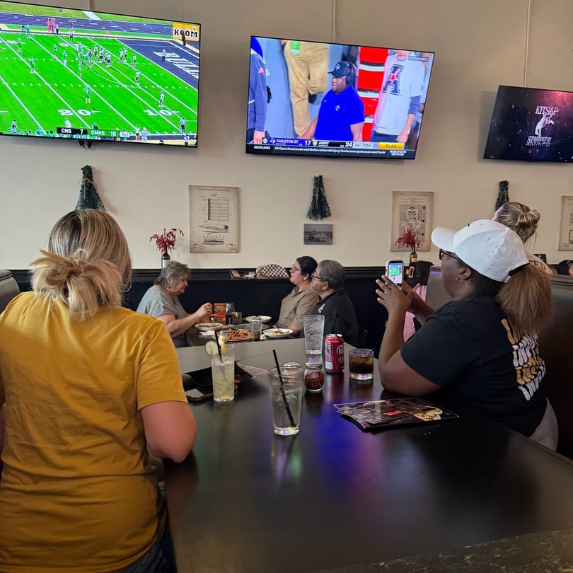 People dining in a casual restaurant with multiple TVs showing sports games.